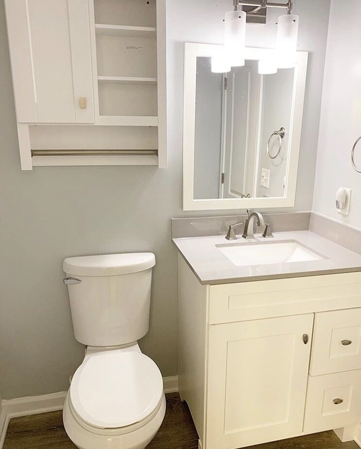 Bathroom with white vanity, toilet and storage cabinet above