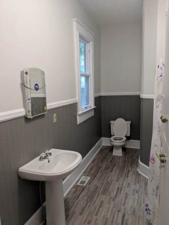 Bathroom with pedestal sink and gray wainscoting