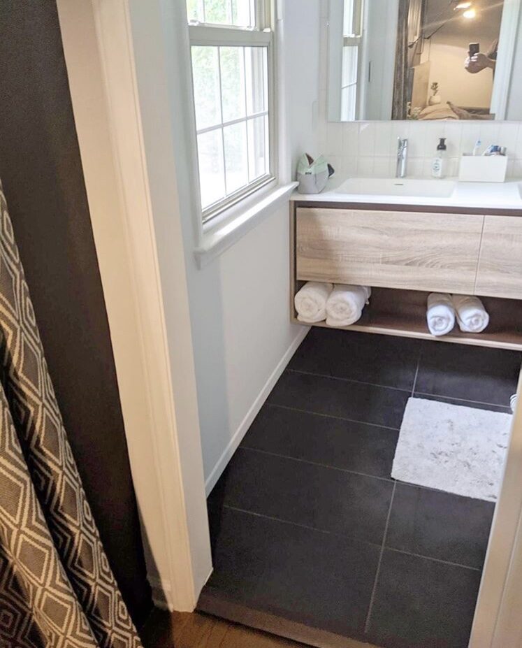 Bathroom with floating wood vanity and dark tile floor