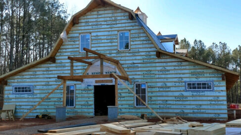 Two-story building wrapped in house wrap during construction